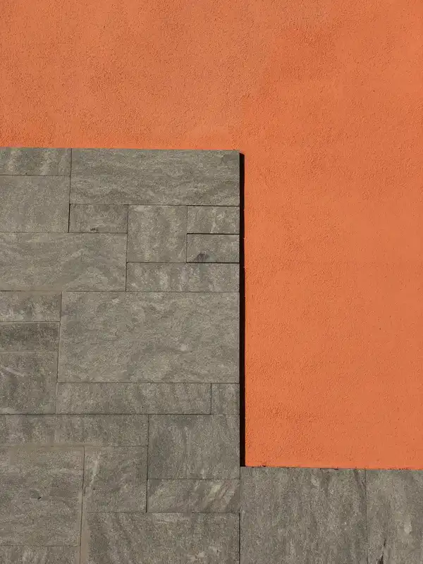 A flat orange wall meeting grey stone blocks in a sharp L-shaped line