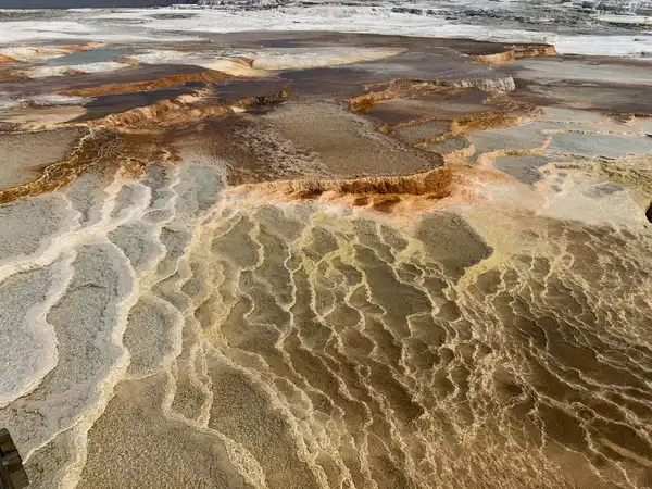 Terraced mineral pools in cream and ochre, seen from above like a contour map
